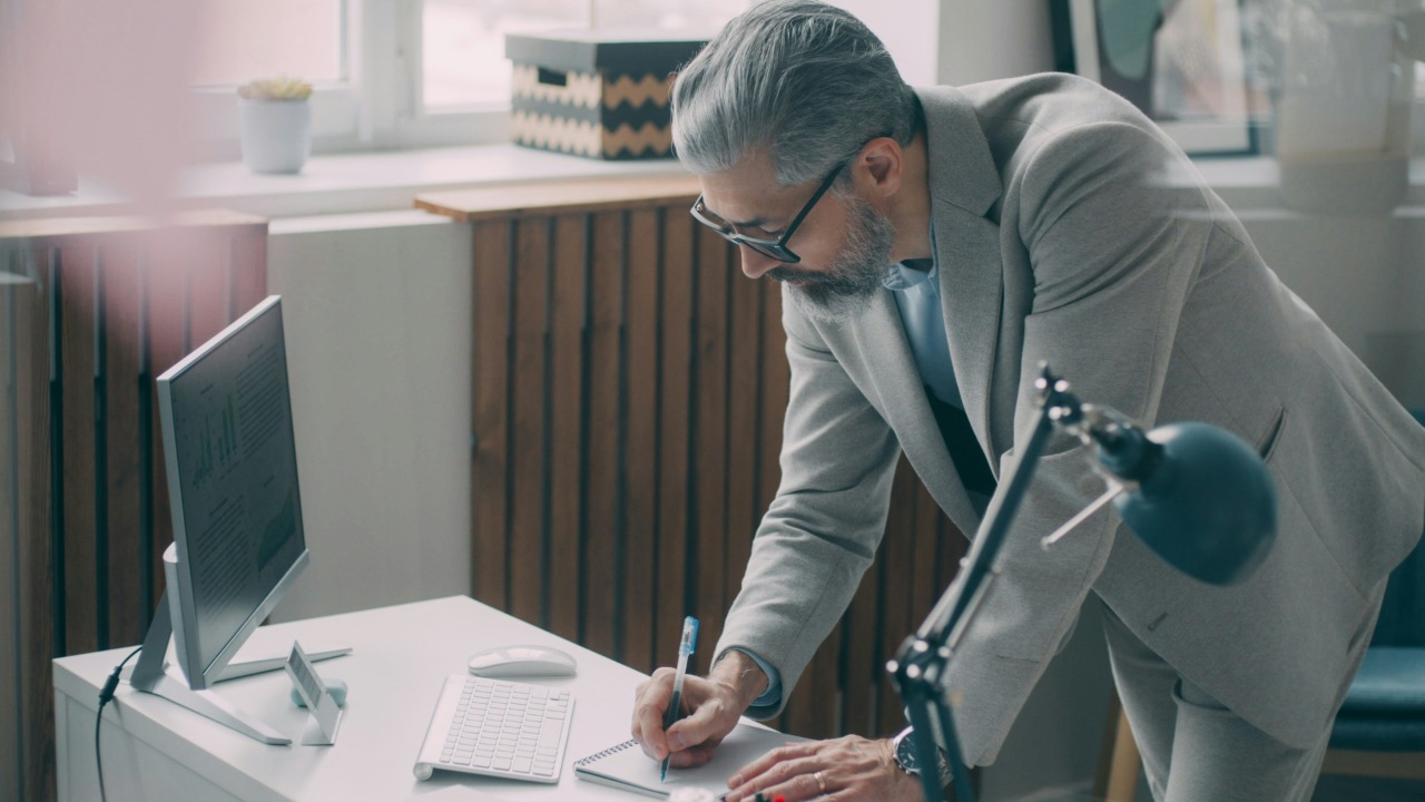 A man in a suit writing on a piece of paper