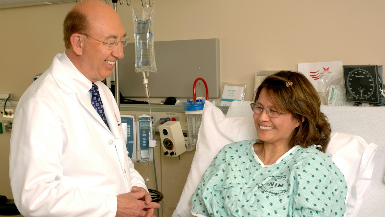 A doctor in a white coat talking to a patient in a hospital bed