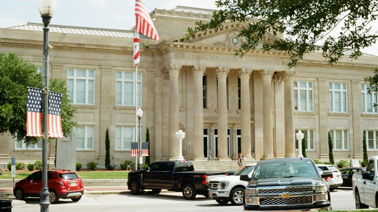 Classical building with columns, american flags, and parked cars