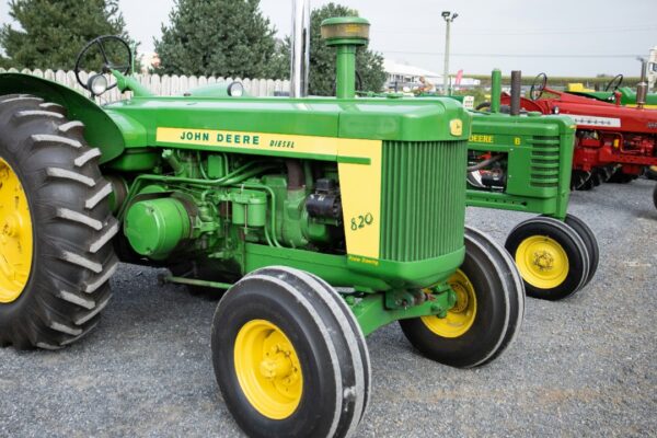 a green tractor parked next to a red tractor