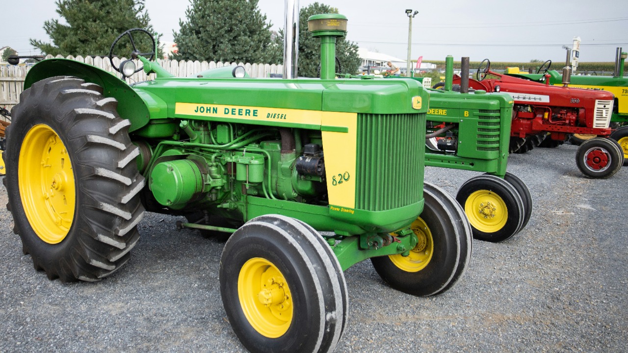 a green tractor parked next to a red tractor