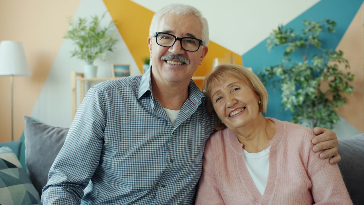 Elderly couple smiling together on a couch