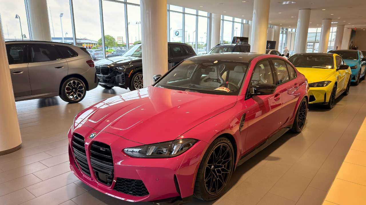 A vibrant pink car displayed prominently in a modern showroom