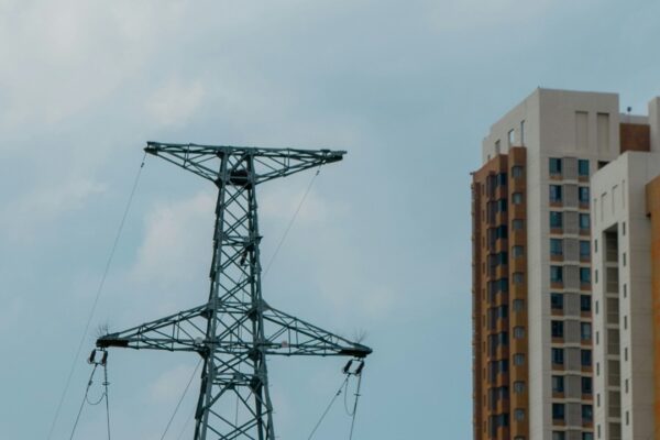 Tall power tower stands next to apartment buildings