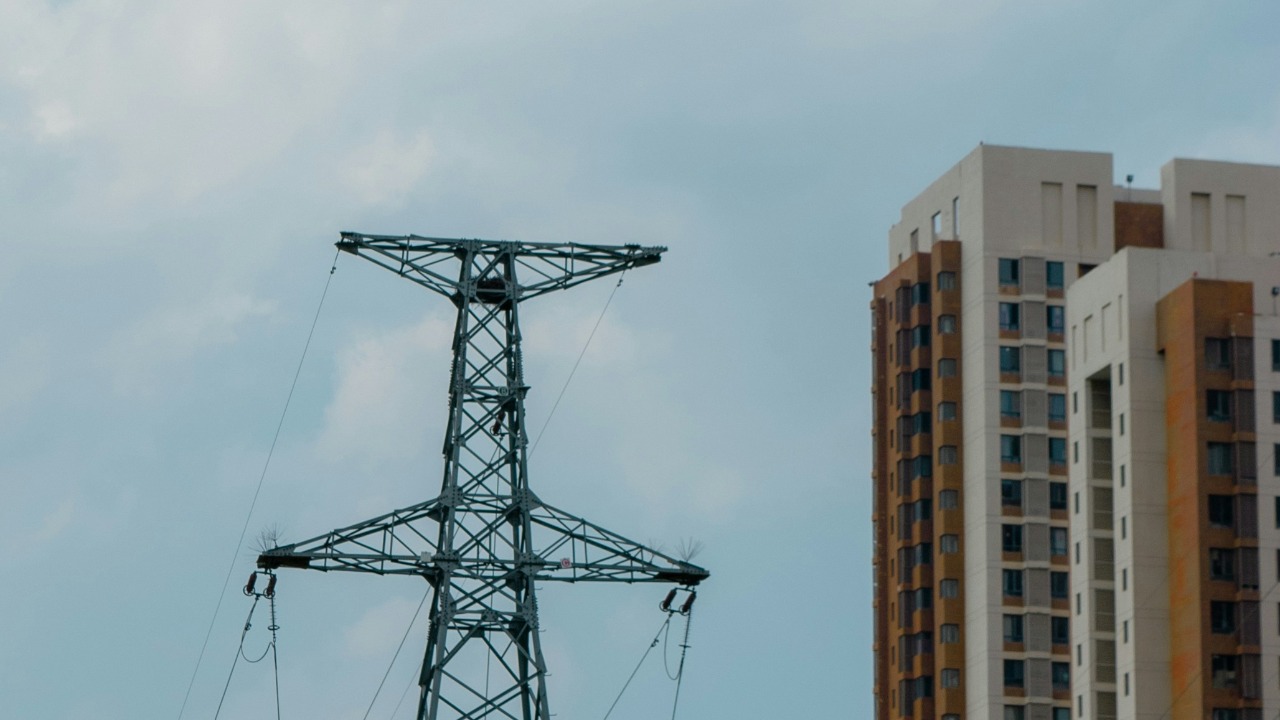 Tall power tower stands next to apartment buildings