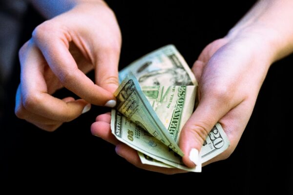 person holding fan of 100 us dollar bill