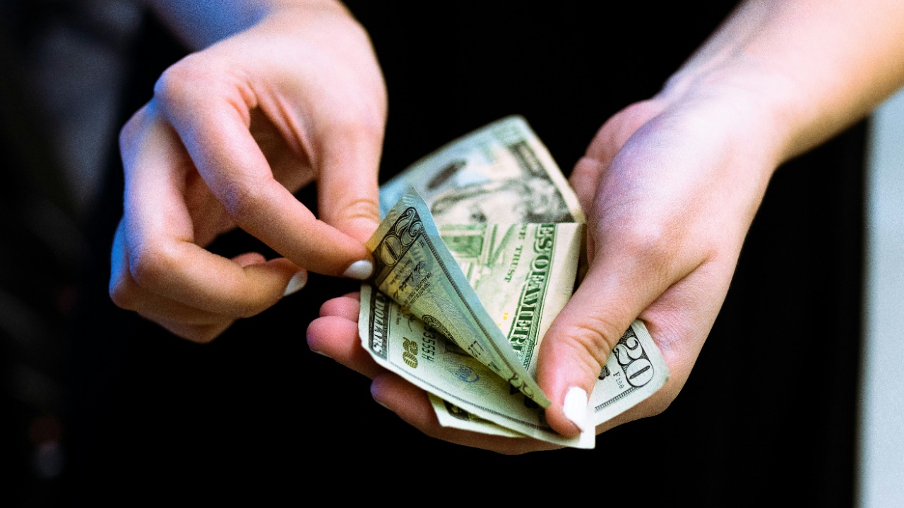 person holding fan of 100 us dollar bill