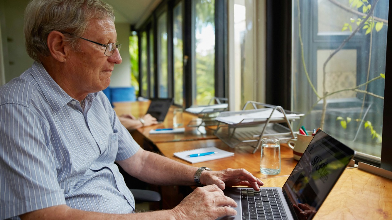 a man sitting at a table using a laptop computer