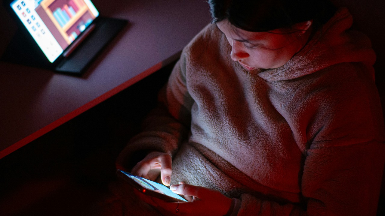 A person sitting in a chair looking at a cell phone