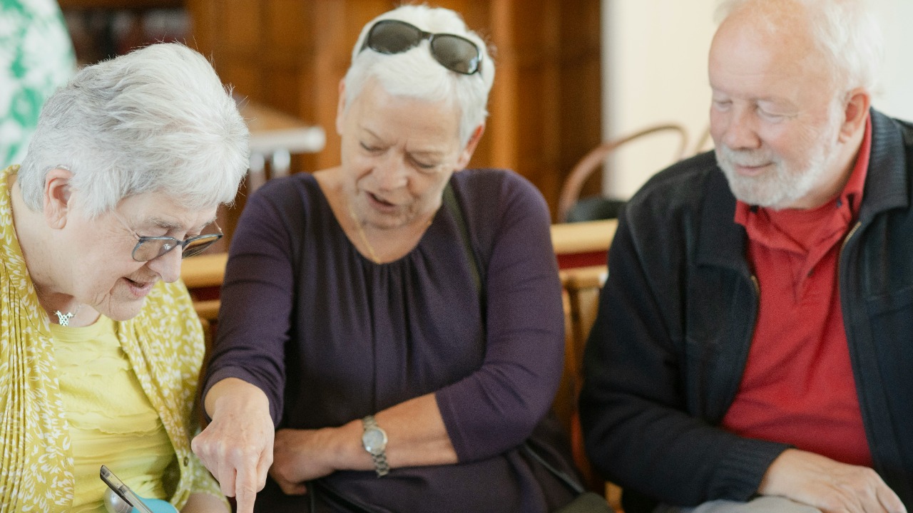 Three older adults are looking at a paper