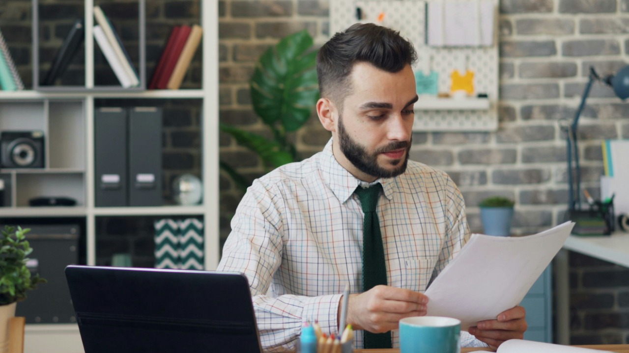 a man sitting at a desk in front of a laptop